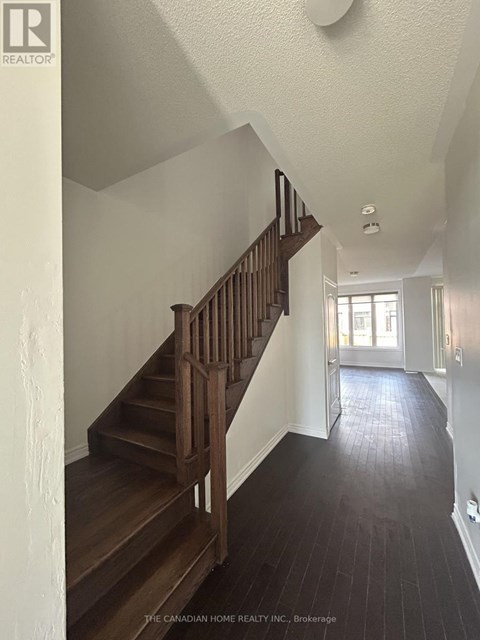 A staircase with a wooden handrail and steps leads to a doorway.