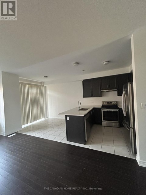 A kitchen with black cabinets and a white fridge.