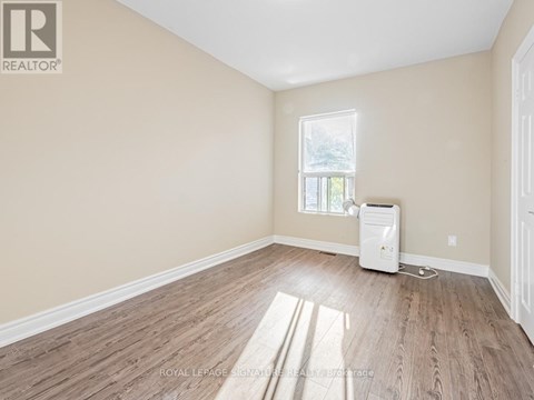A room with wooden flooring and a window with sunlight coming through.