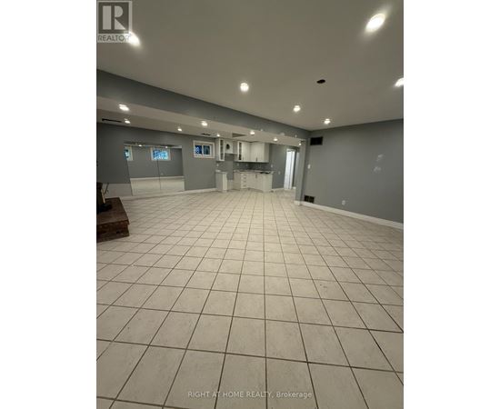 A spacious room with tile flooring and grey walls.