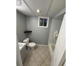 A small bathroom with a toilet, sink, and a window.