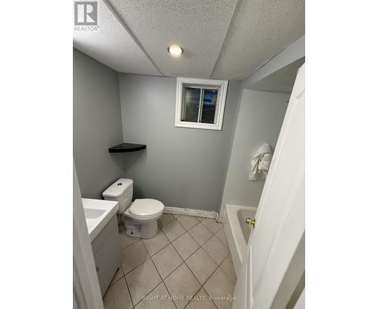 A small bathroom with a toilet, sink, and a window.