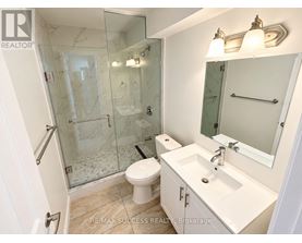 A white bathroom with a glass shower stall and a toilet.