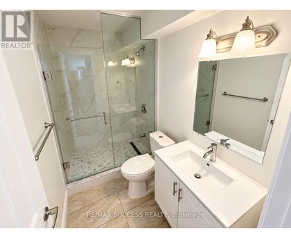 A white bathroom with a glass shower stall and a toilet.