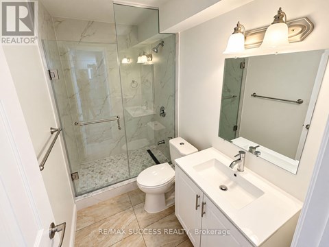 A white bathroom with a glass shower stall and a toilet.