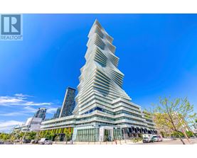 A tall, modern building with a unique design stands under a clear blue sky.