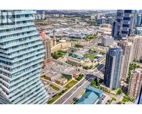 A cityscape with a mix of modern and older buildings, a large open space in the center, and a clear sky.