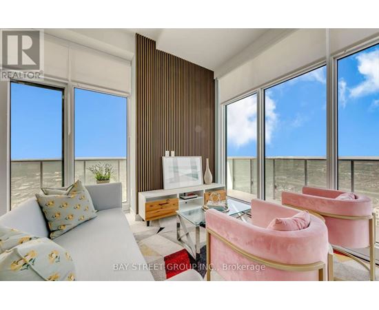 A living room with a couch, chairs, and a large window overlooking the beach.