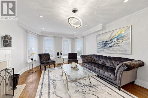 A living room with a grey sofa, a glass coffee table, and a painting on the wall.
