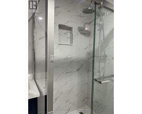 A shower with a marble wall and a glass door.