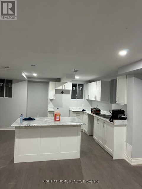 A kitchen with white cabinets and a marble countertop.