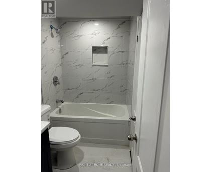 A white bathroom with a marble wall and a bathtub.