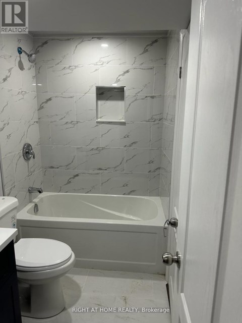 A white bathroom with a marble wall and a bathtub.