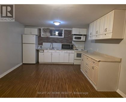 A kitchen with white cabinets and a wooden floor.