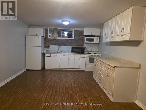 A kitchen with white cabinets and a wooden floor.