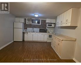 A kitchen with white cabinets and wooden floors.