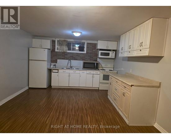 A kitchen with white cabinets and wooden floors.