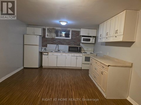 A kitchen with white cabinets and wooden floors.