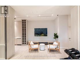 A modern living room with a large painting, a sofa, a chair, and a potted plant.