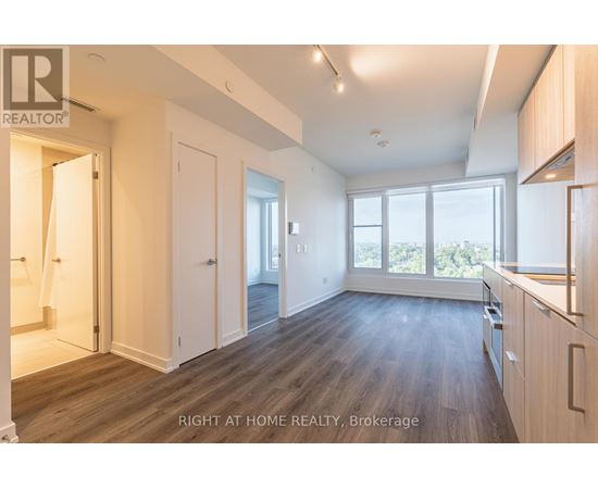 A spacious room with wooden flooring and white walls.