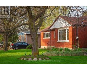A house with a red brick exterior and a tree in front.