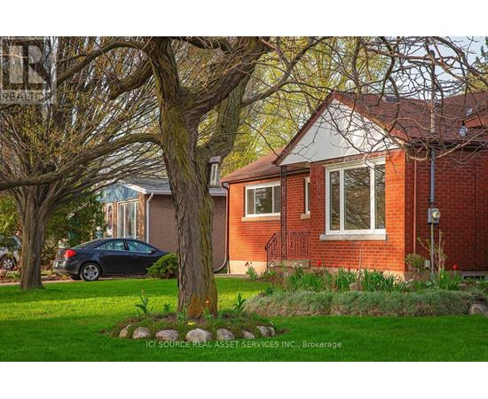 A house with a red brick exterior and a tree in front.