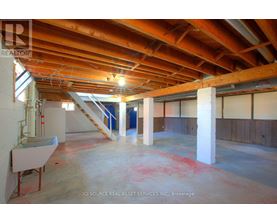 A large empty room with a wooden ceiling and a staircase.