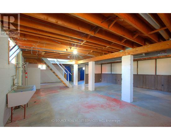 A large empty room with a wooden ceiling and a staircase.