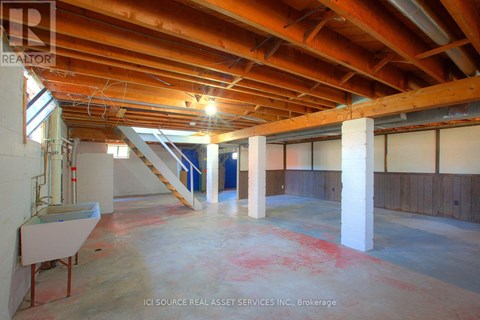 A large empty room with a wooden ceiling and a staircase.