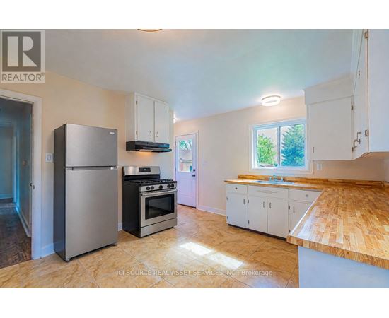 A kitchen with a refrigerator, oven, and cabinets.