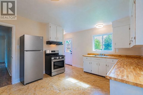 A kitchen with a refrigerator, oven, and cabinets.