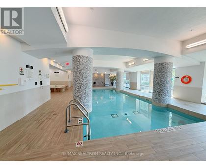 A pool inside a building with a sign that says RE/MAX REALTRON REALTY INC., Brokerage.