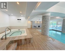 A hot tub in a room with a wooden floor and a wall with a window.