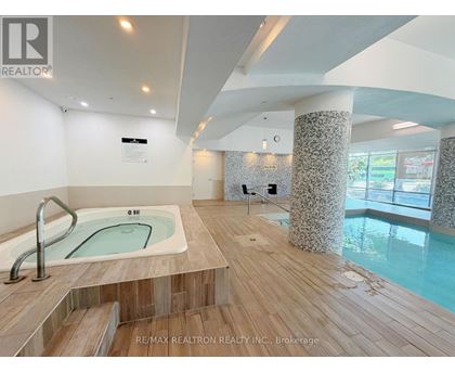 A hot tub in a room with a wooden floor and a wall with a window.