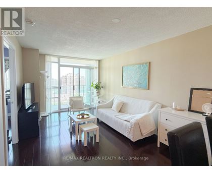 A living room with a white couch and a painting on the wall.