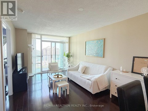A living room with a white couch and a painting on the wall.