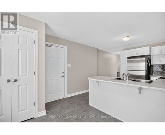 A kitchen area with white cabinets and a stainless steel fridge.