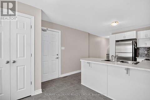 A kitchen area with white cabinets and a stainless steel fridge.