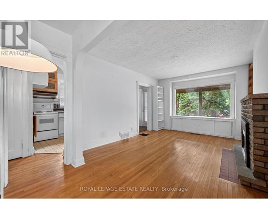 A room with wooden floors and white walls, with a window overlooking trees.