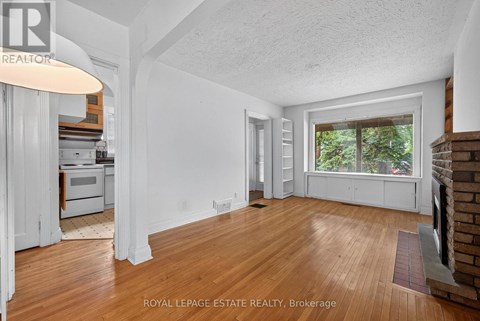 A room with wooden floors and white walls, with a window overlooking trees.