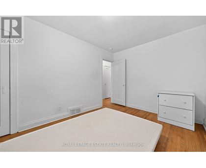 A white bedroom with a bed, dresser and nightstand.