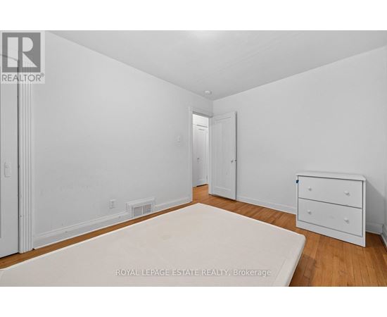 A white bedroom with a bed, dresser and nightstand.