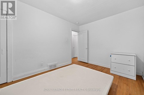 A white bedroom with a bed, dresser and nightstand.