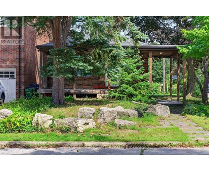 A house with a porch surrounded by rocks and trees.
