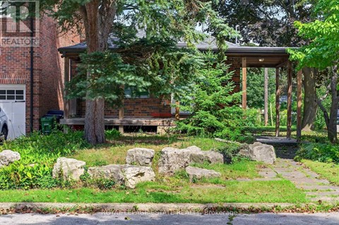 A house with a porch surrounded by rocks and trees.
