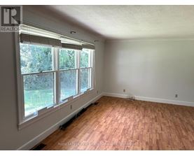 A room with wooden flooring and large windows.