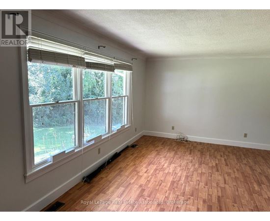 A room with wooden flooring and large windows.