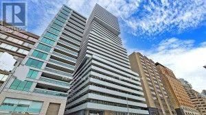A tall building with many windows is under a blue sky.