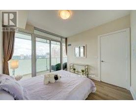 A bedroom with a large bed and a window overlooking a balcony.