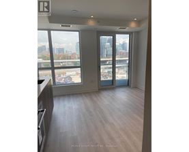 A spacious room with a view of the cityscape through large windows.